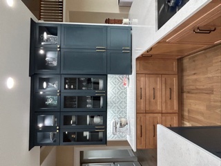 Light wood kitchen cabinets with indigo furniture-style accents and white quartz countertops