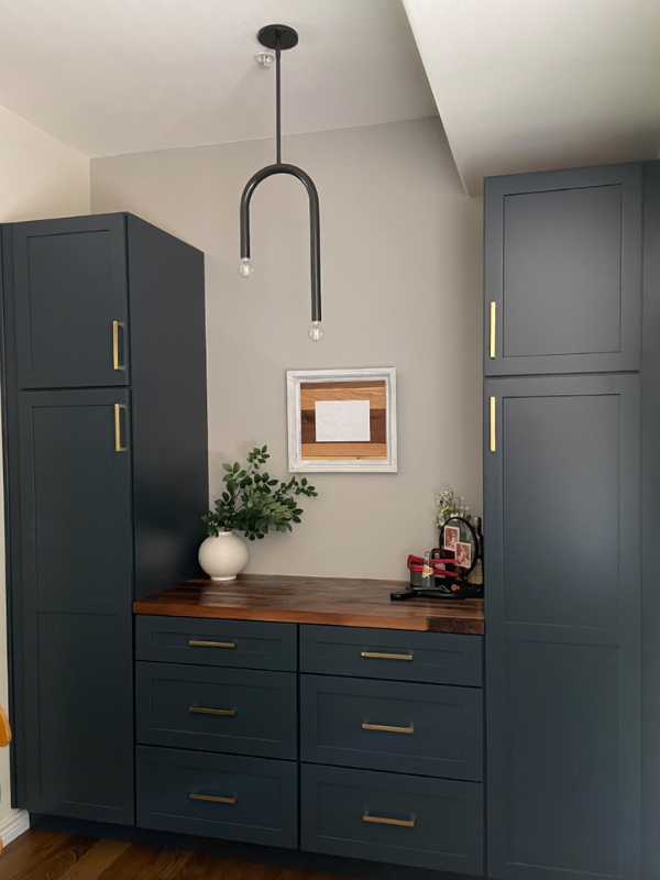 Dark indigo shaker cabinet bar with butcher block countertop flanked by tall pantries on either end