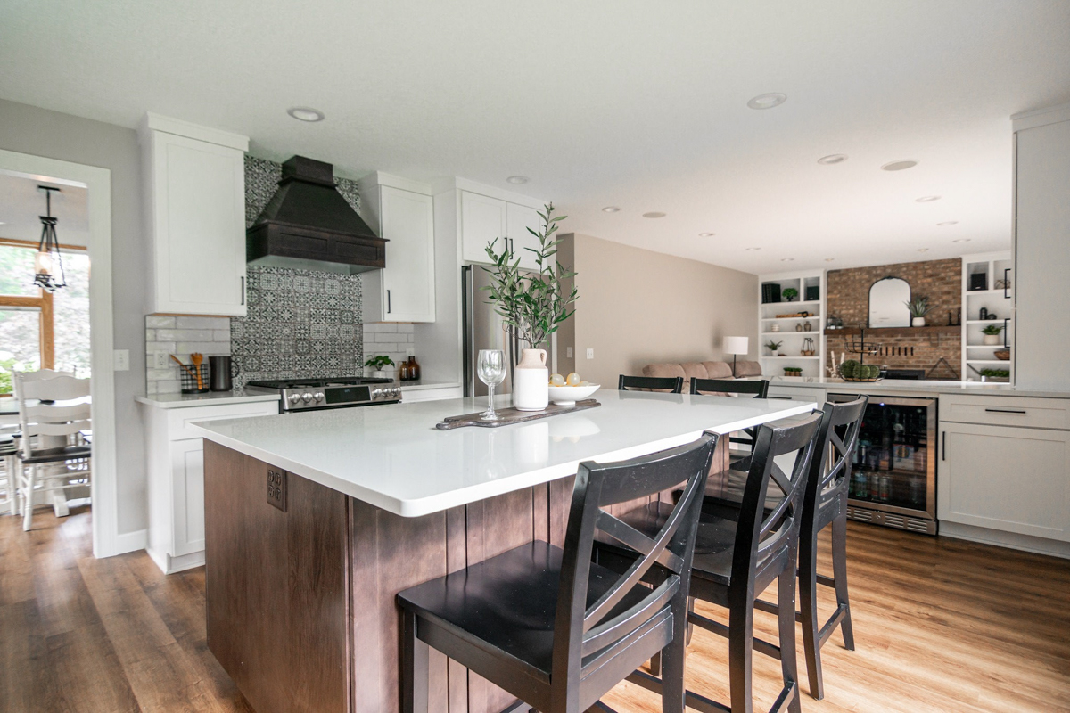 White shaker kitchen and crown molding with dark brown kitchen hood and island with white quartz countertops