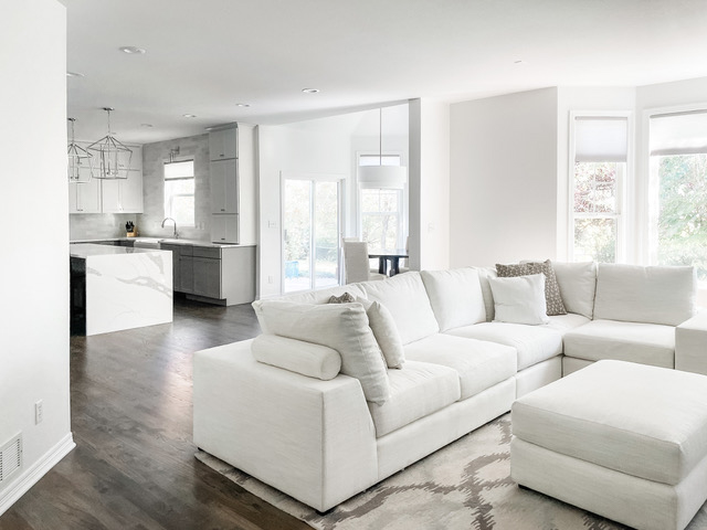 White and light gray shaker kitchen cabinets with white quartz waterfall countertops and polished chrome light fixtures