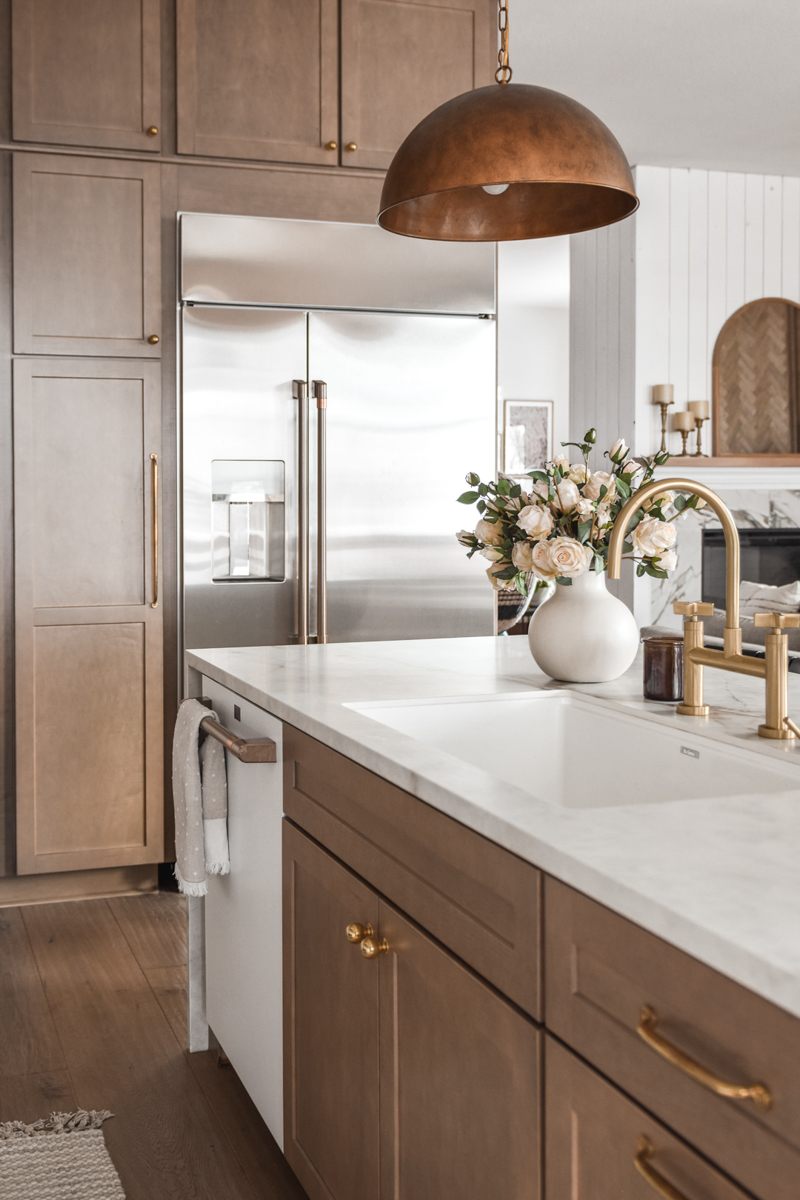 Light wood shaker kitchen cabinets and island with a cream-colored half waterfall island countertop