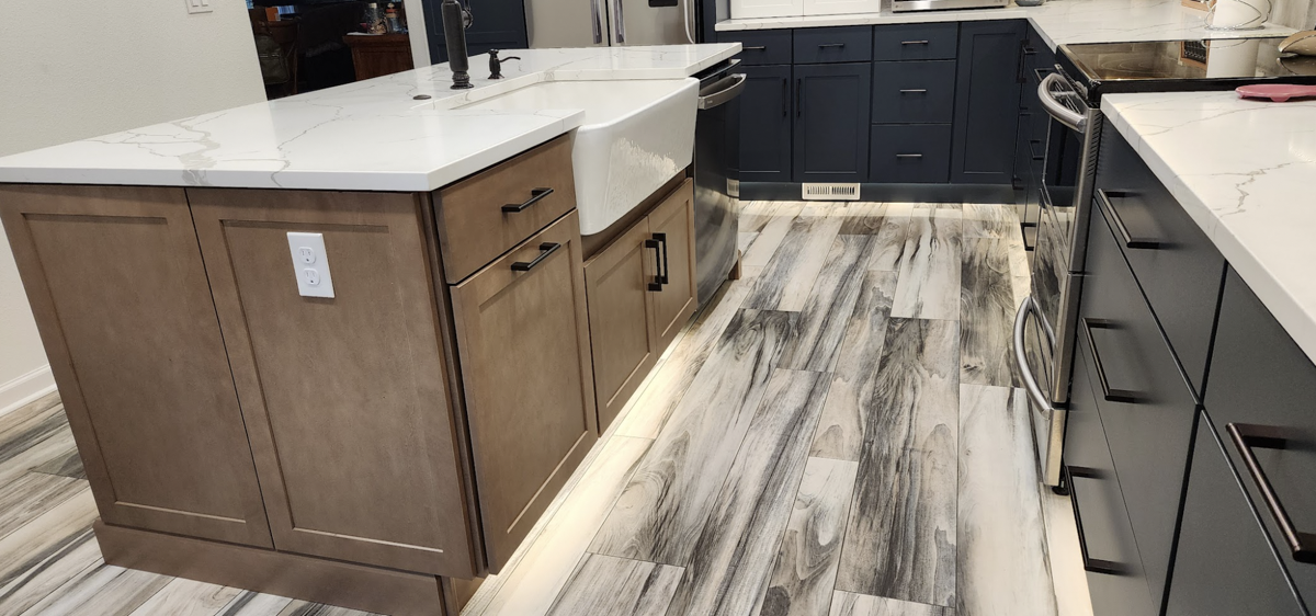 Farmhouse kitchen with white shaker wall cabinets, blue shaker base cabinets, and light wood furniture-style island