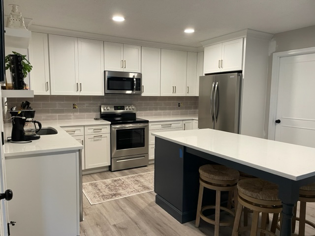 White shaker kitchen design with a dark indigo-blue island with furniture legs and seating