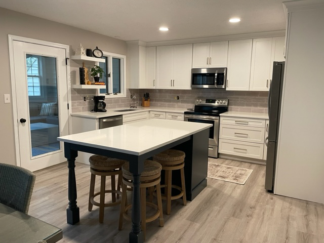 White shaker kitchen design with a dark indigo-blue island with furniture legs and seating