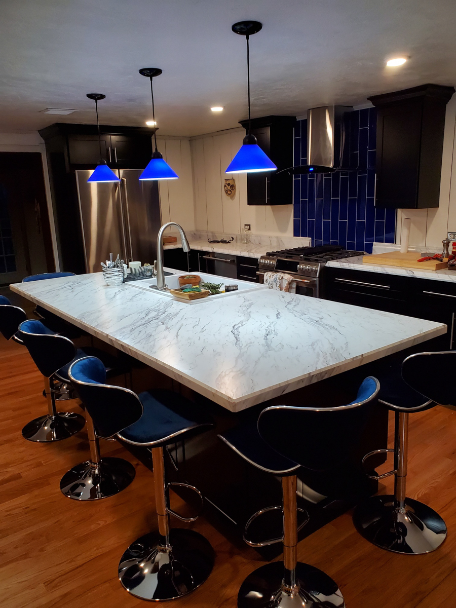 Black shaker kitchen cabinets with white countertops, blue lighting, and blue subway tile backsplash