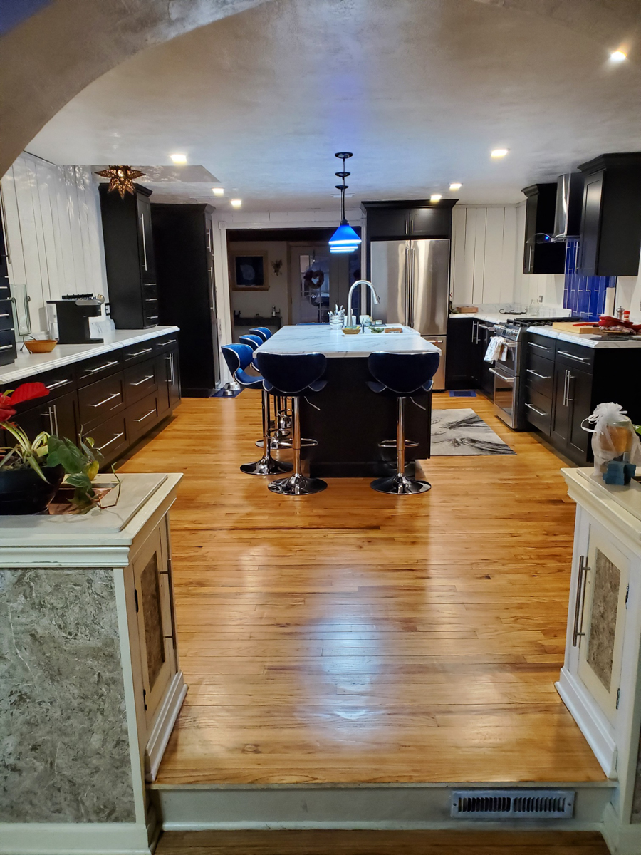 Black shaker kitchen cabinets with white countertops, blue lighting, and blue subway tile backsplash