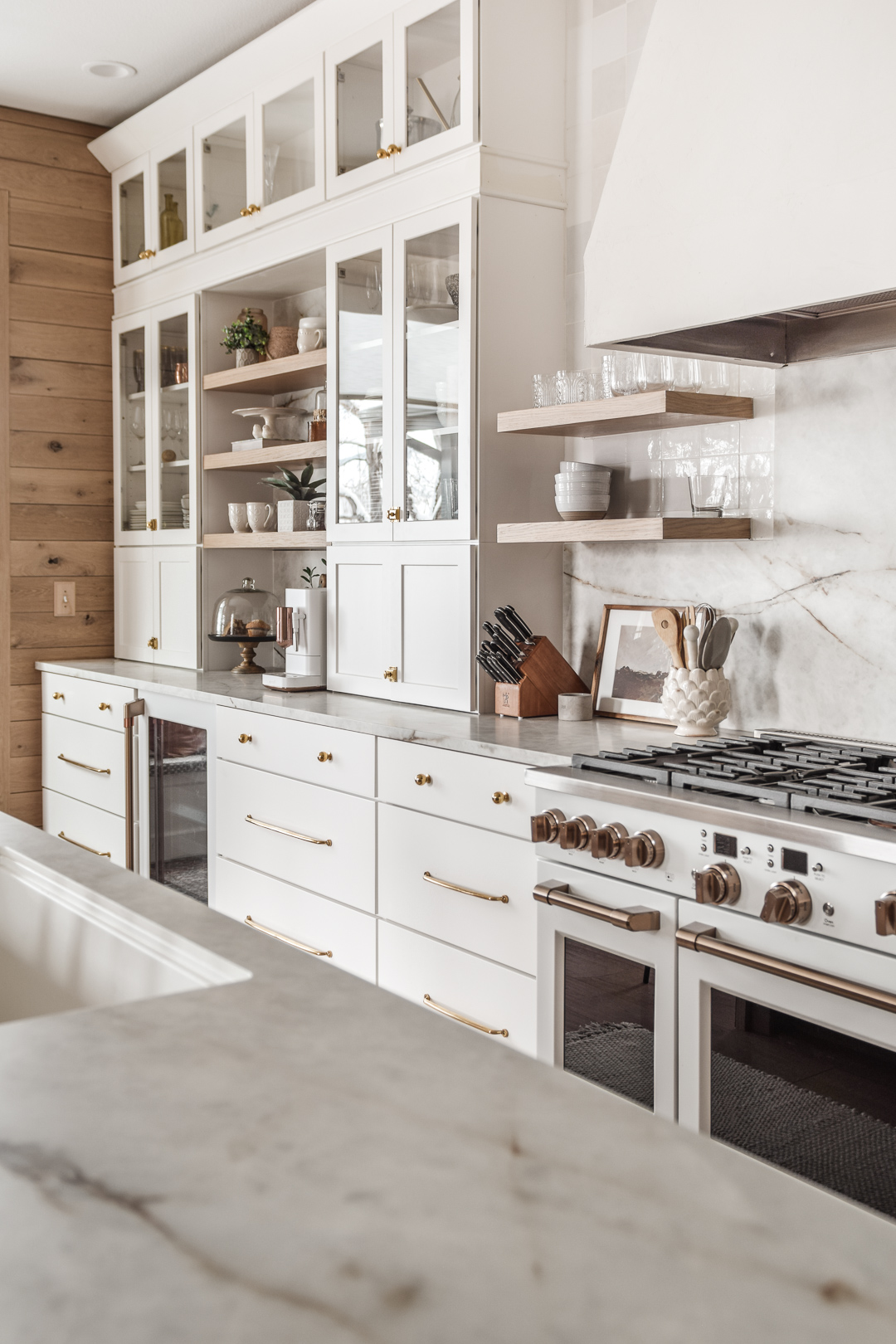 Shaker white kitchen cabinets with a white and gold range and cream and brown marble countertops