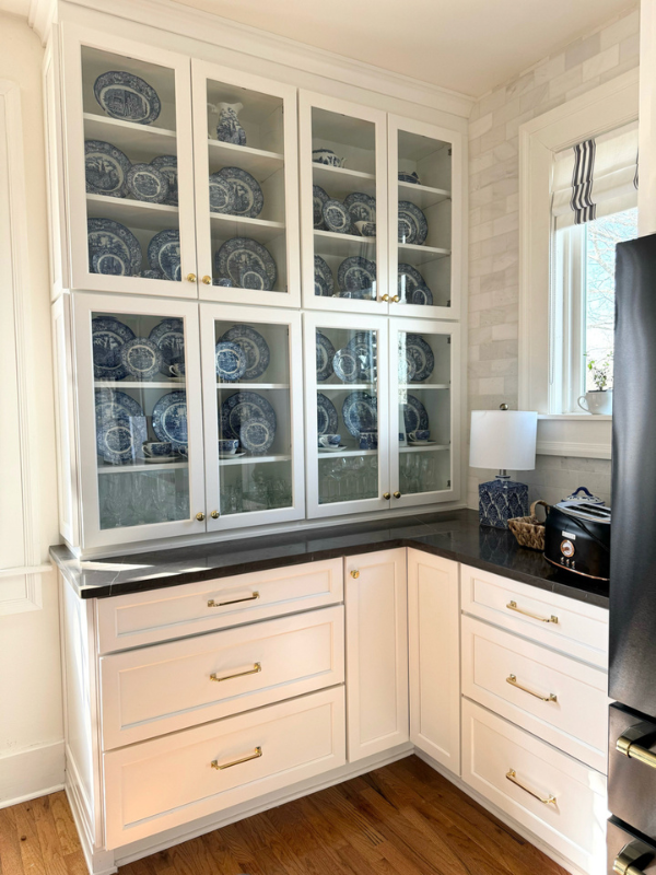 Grand white shaker kitchen design with matching wood hood and stacked glass cabinets