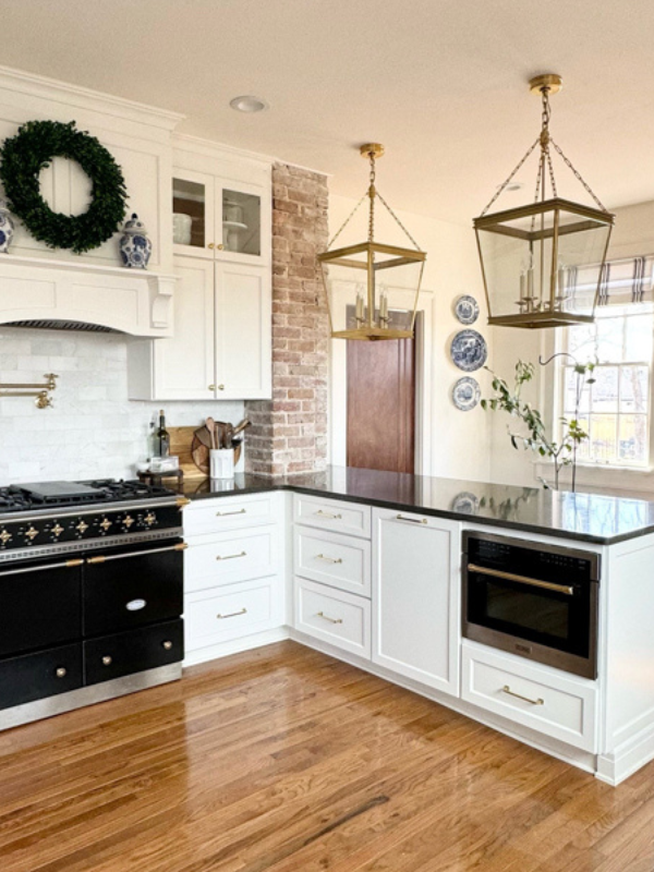 Grand white shaker kitchen design with matching wood hood and stacked glass cabinets