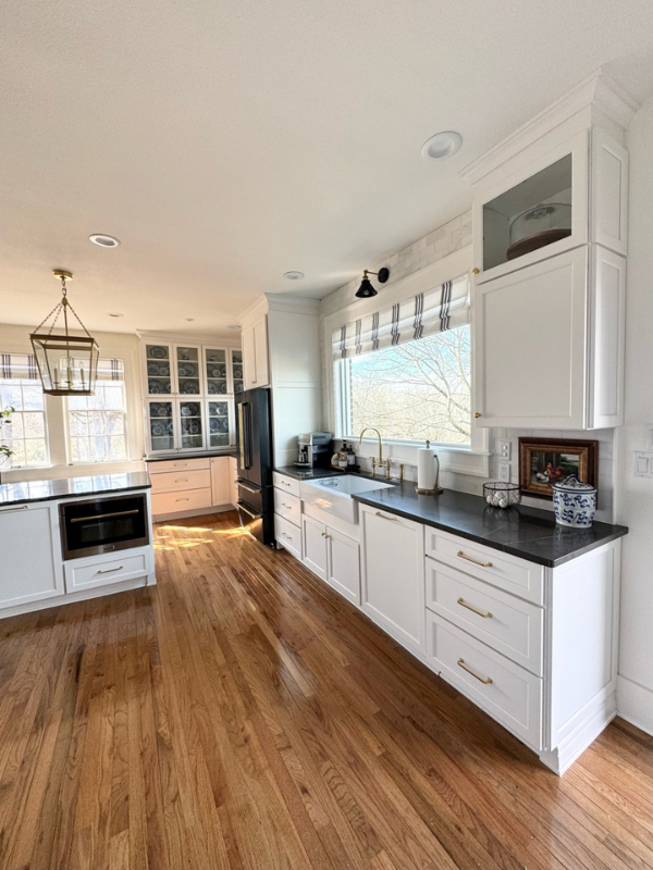 Grand white shaker kitchen design with matching wood hood and stacked glass cabinets