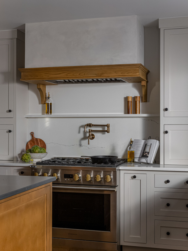 European kitchen design with cream inset cabinets and wood accents with a plaster kitchen hood