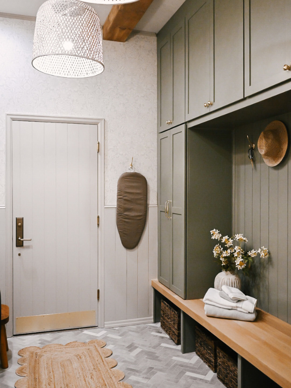 Right side of the laundry room with light olive mudroom lockers flanking a white oak bench with woven baskets below and cement pavers in herringbone floor pattern