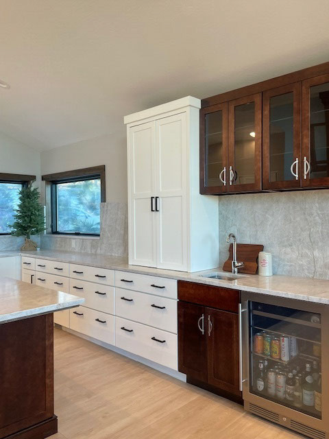 Large white shaker kitchen with a large dark brown wood island and creamy stone countertops