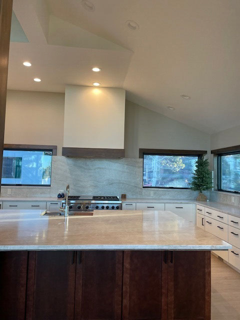 Large white shaker kitchen with a large dark brown wood island and creamy stone countertops