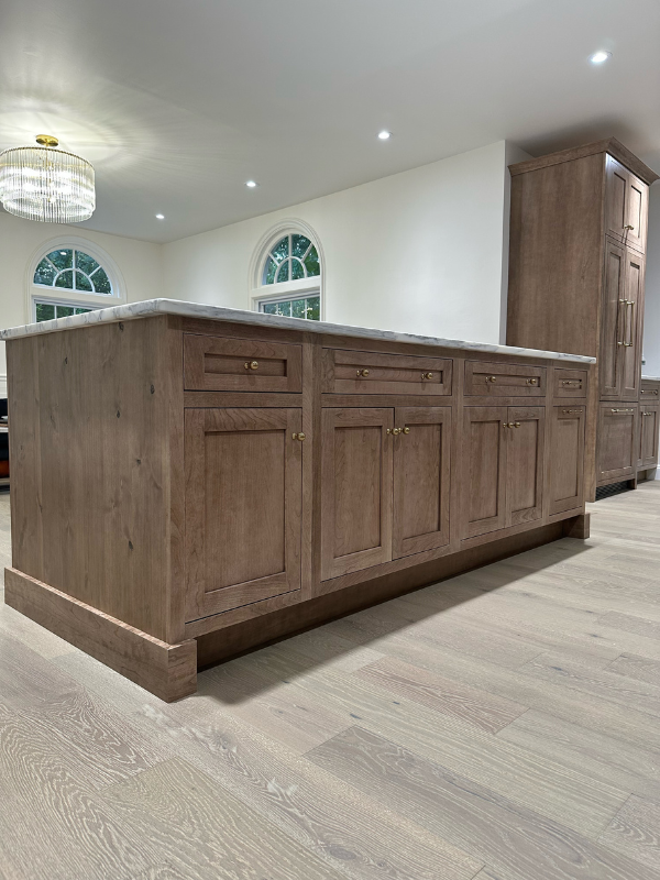 Medium-brown inset kitchen island cabinets with baseboard molding and white stone countertops