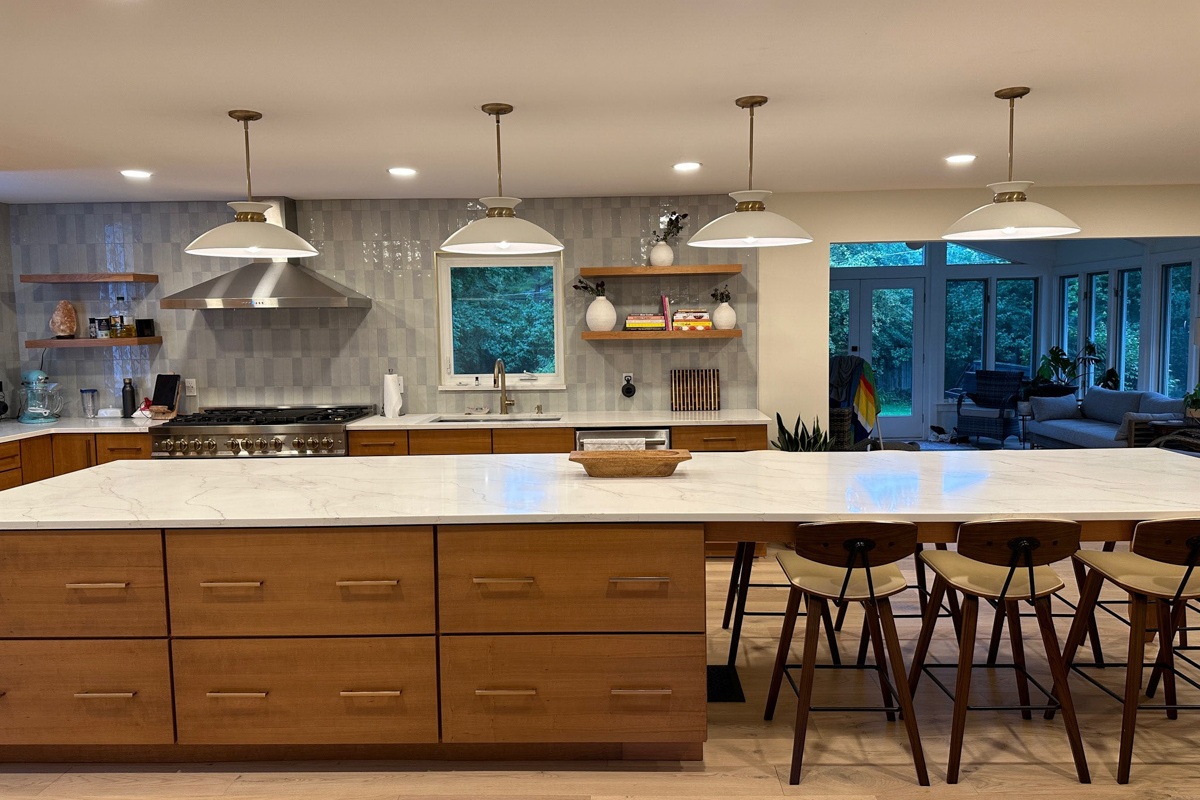 Mid-century modern kitchen with cherry slab door cabinets with a stainless steel kitchen hood, massive island with seating and marble imitation quartz countertops