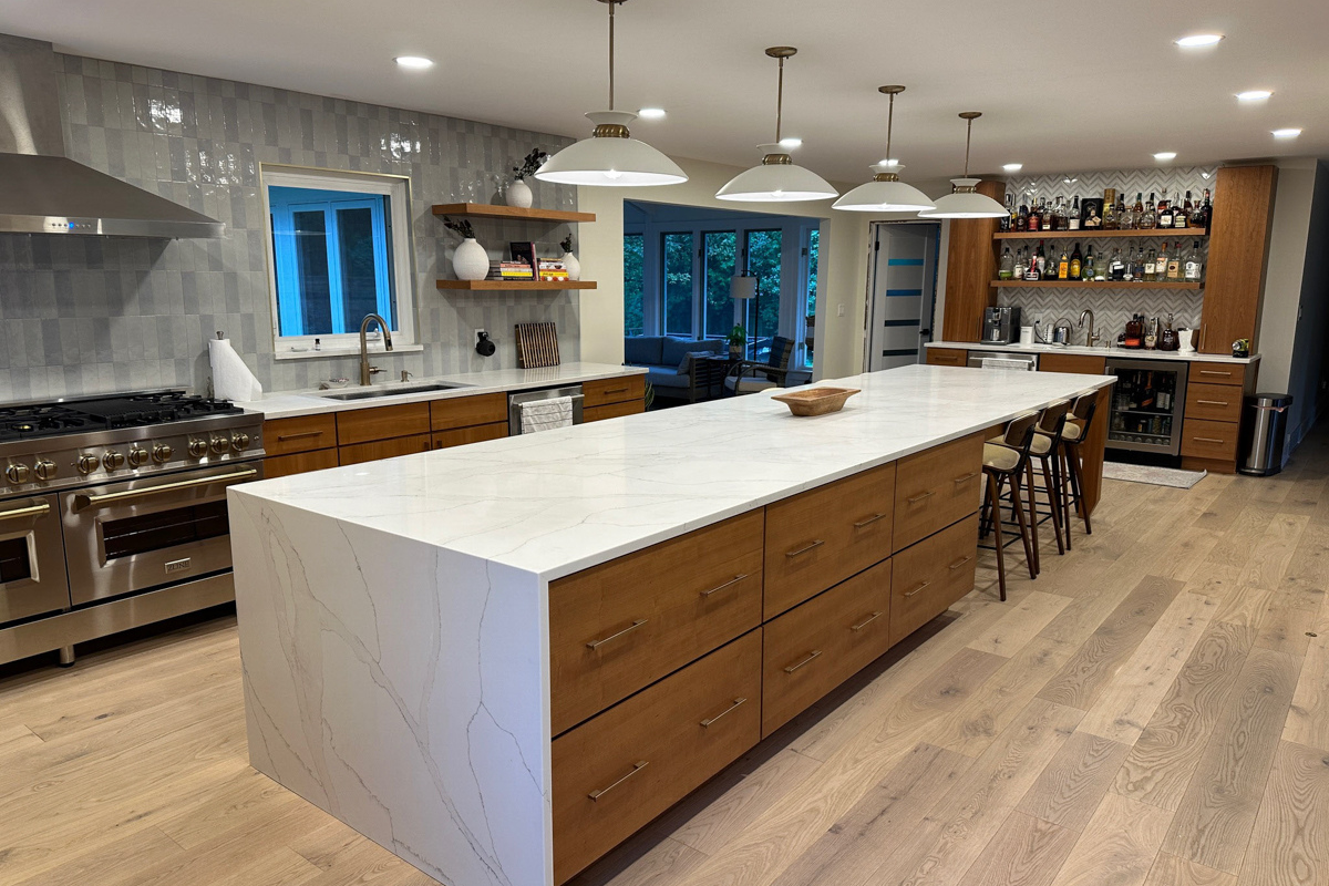 Mid-century modern kitchen with cherry slab door cabinets with a stainless steel kitchen hood, massive island with seating and marble imitation quartz countertops