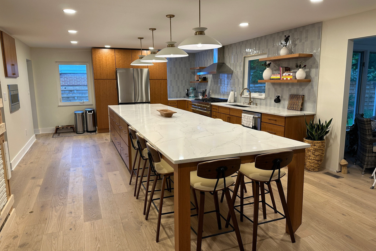 Mid-century modern kitchen with cherry slab door cabinets with a stainless steel kitchen hood, massive island with seating and marble imitation quartz countertops