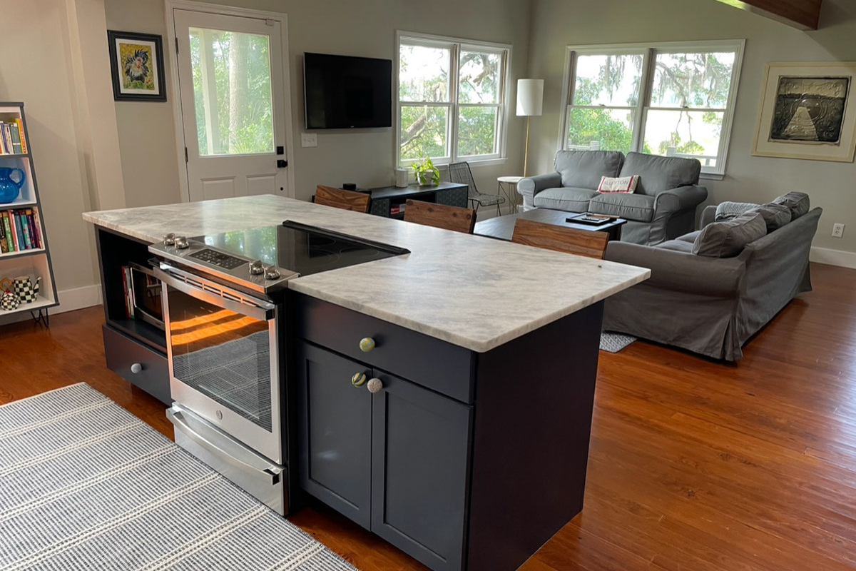 Navy blue shaker kitchen island cabinets with a slide-in range, microwave shelf, and white and gray quartz countertops