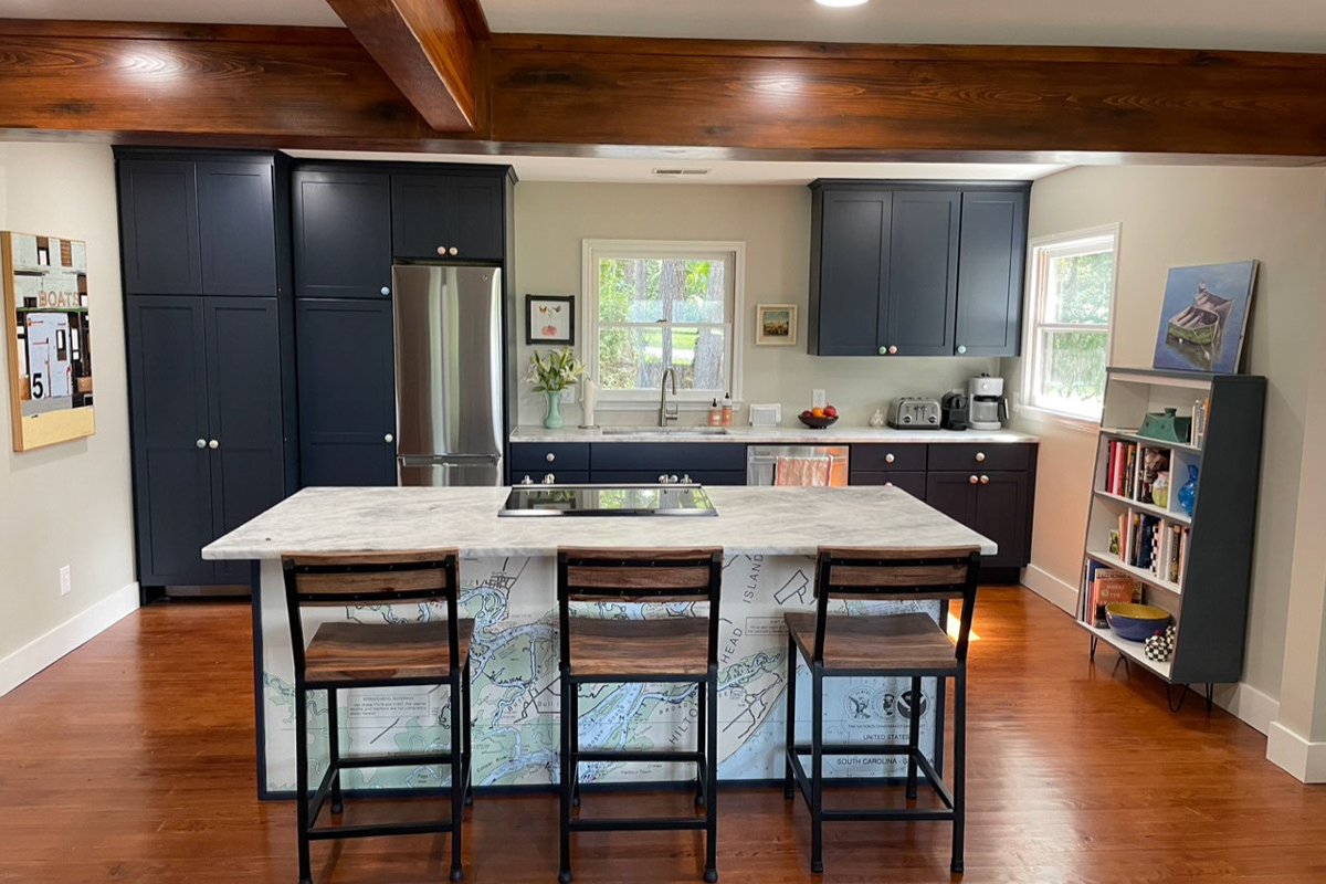 One-wall kitchen remodel with island in navy blue shaker kitchen cabinets with a white and gray quartz countertop and unique map of hilton head on the back of the island