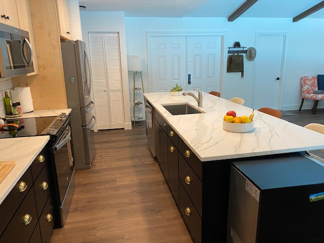 L-shaped kitchen design and island with black shaker base cabinets and natural maple wall cabinets.