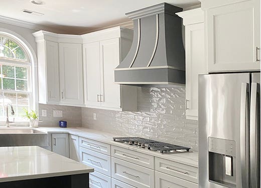 Dark gray wood range hood with steel strapping against white shaker kitchen cabinets