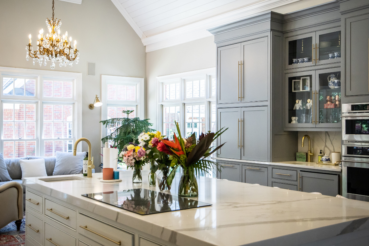 Custom blue inset kitchen cabinets and white quartz countertops with a gold chandelier