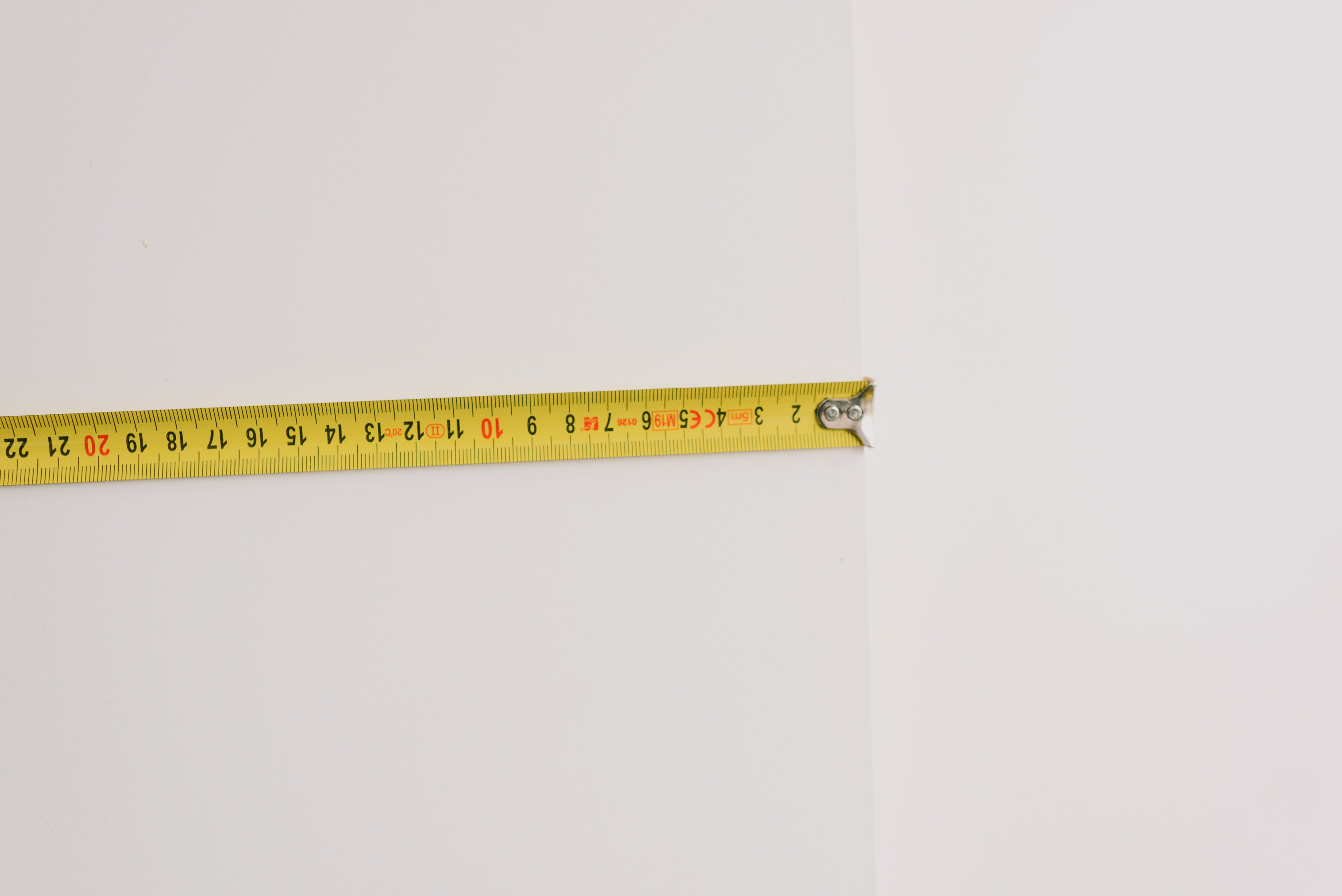 Person using tape measure to measure the length of a wall Person using tape measure to measure the length of a wall