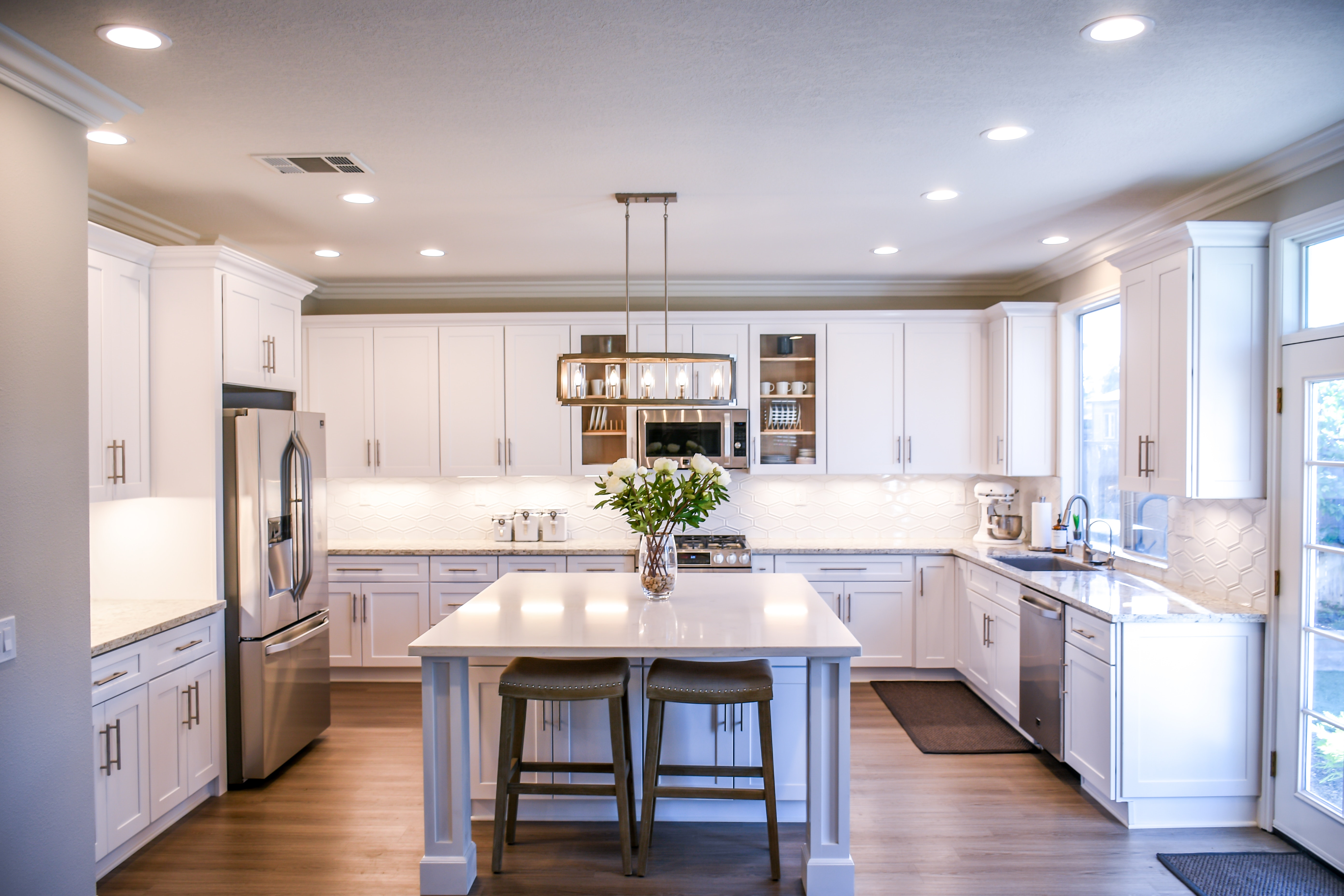 White shaker kitchen with can lighting, pendant lighting, and under-cabinet lighting.