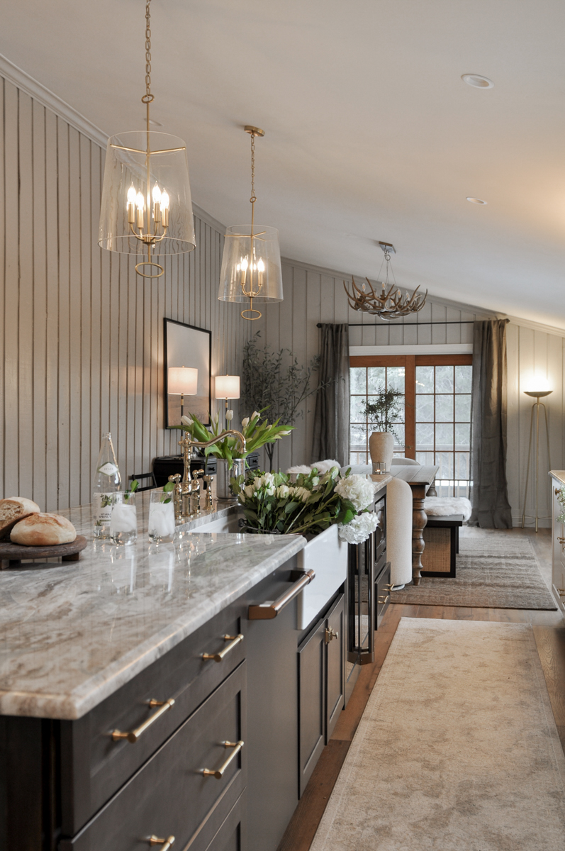 Large dark brown furniture-style shaker island cabinets with brass hardware and cream and brown marble countertops with an ogee edge profile