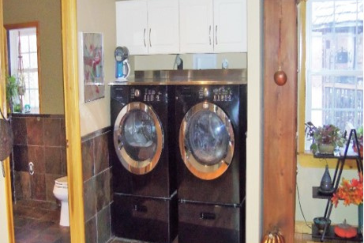 White shaker wall cabinets suspended over a frontload washer and dryer