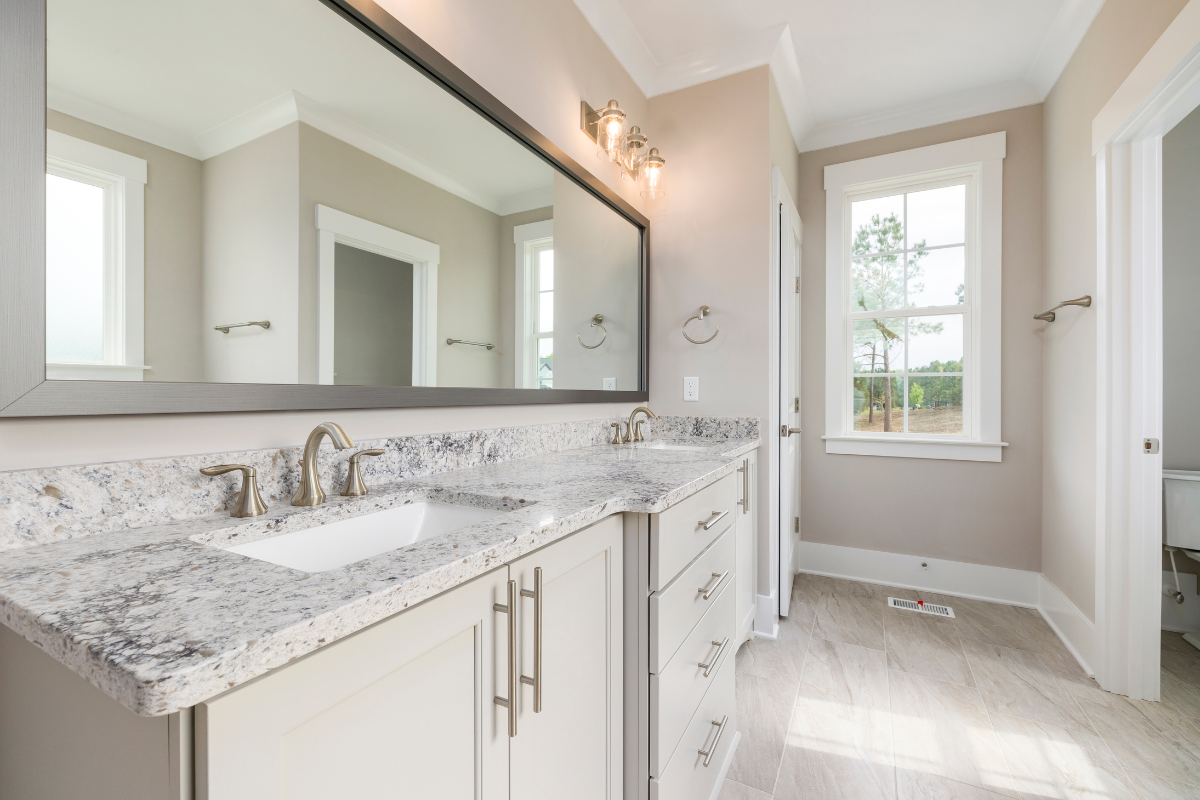 Decorative white bathroom vanity with light granite countertops and brushed nickel fixtures