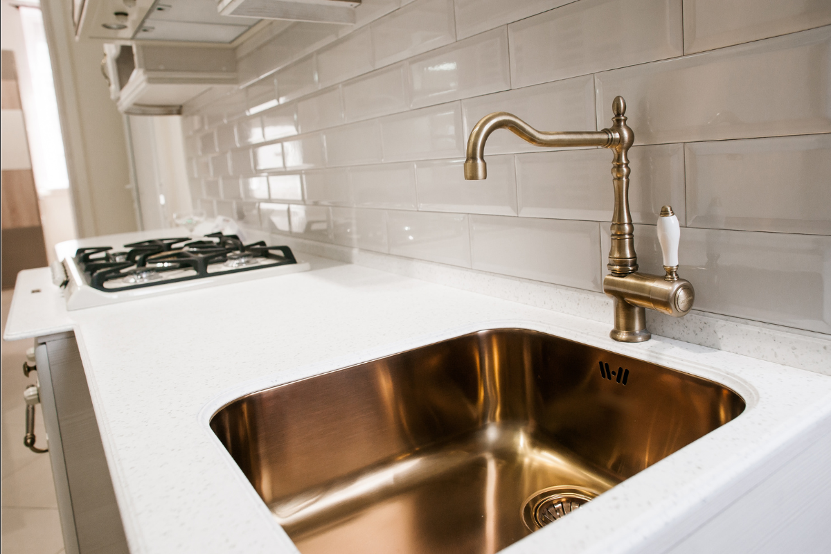 Vintage and traditional gold kitchen sink faucet next to a bronze undermount kitchen sink