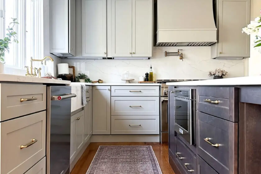 Light gray shaker kitchen with dark wood stained island and white marble-like countertops