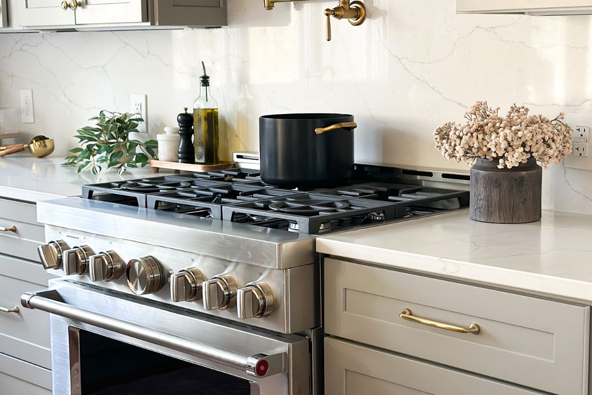 Light gray shaker kitchen cabinets with a large KitchenAid gas range and white quartz countertops