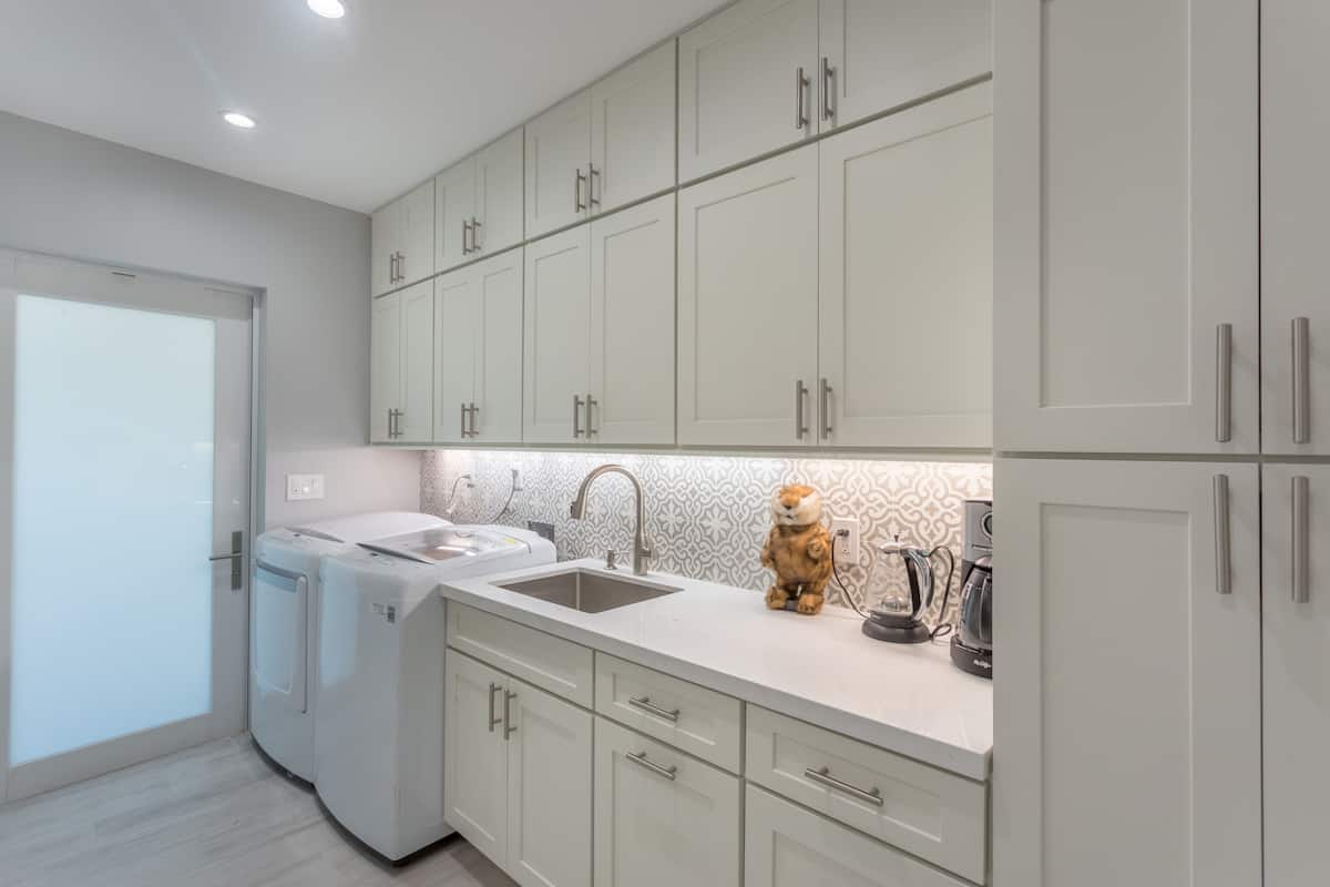 Stacked white shaker laundry room cabinets with white quartz countertops