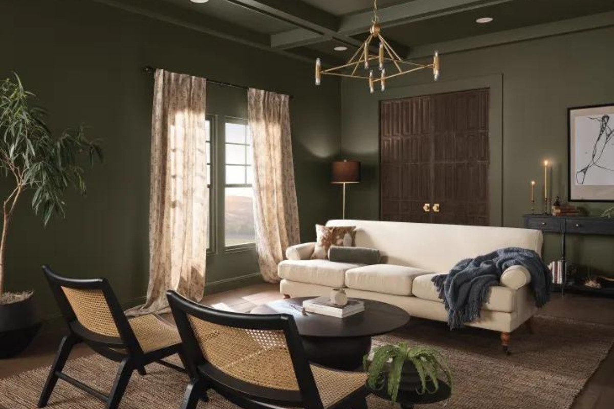 Moody living room with dark olive green wall paint and furniture with cream and tan finishes