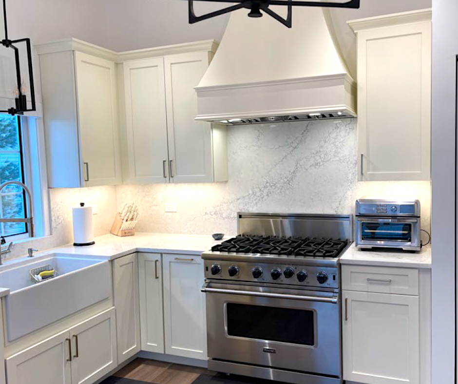 CliqStudios project: cream-colored shaker kitchen cabinets with a matching wood hood and large stainless steel gas range