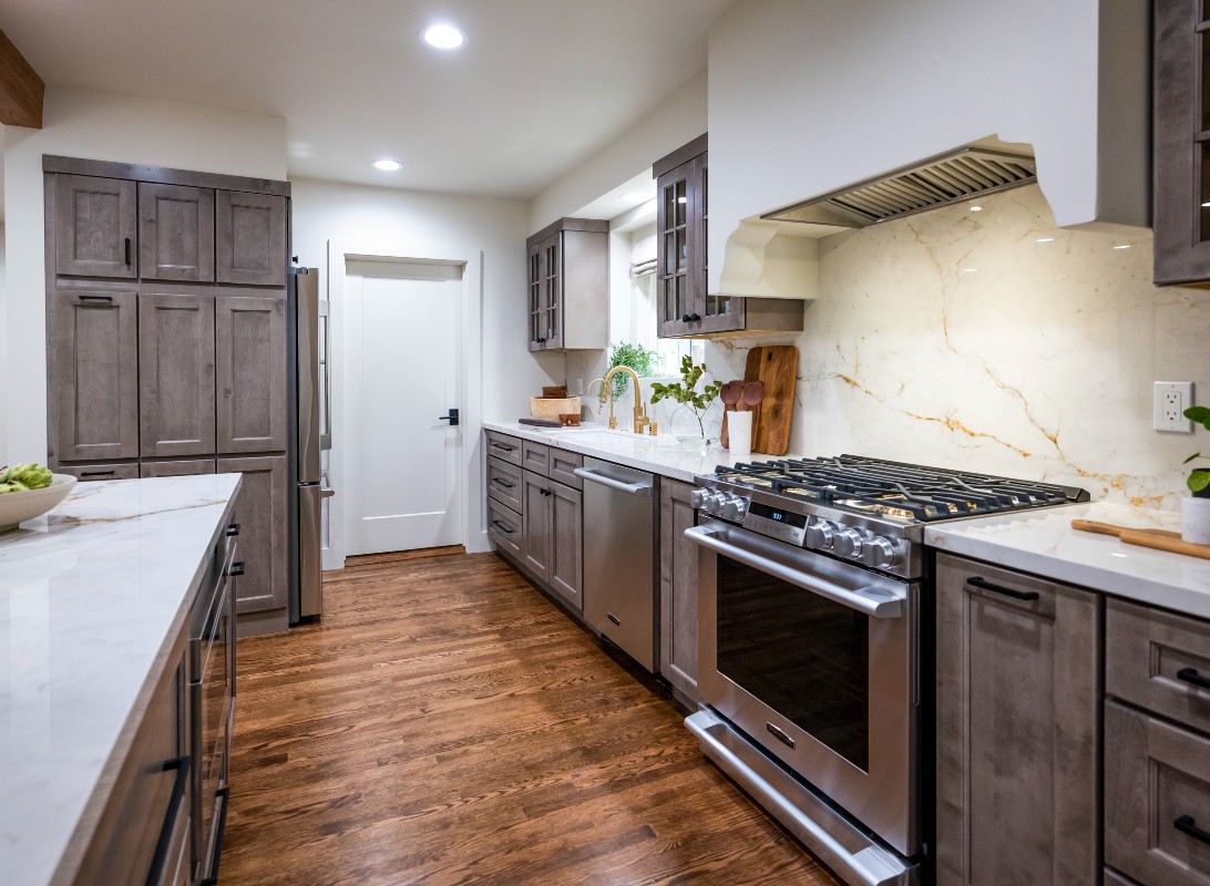 CliqStudios project: Light gray-brown stained kitchen cabinets with mullion doors, cream countertops, and a slab backsplash