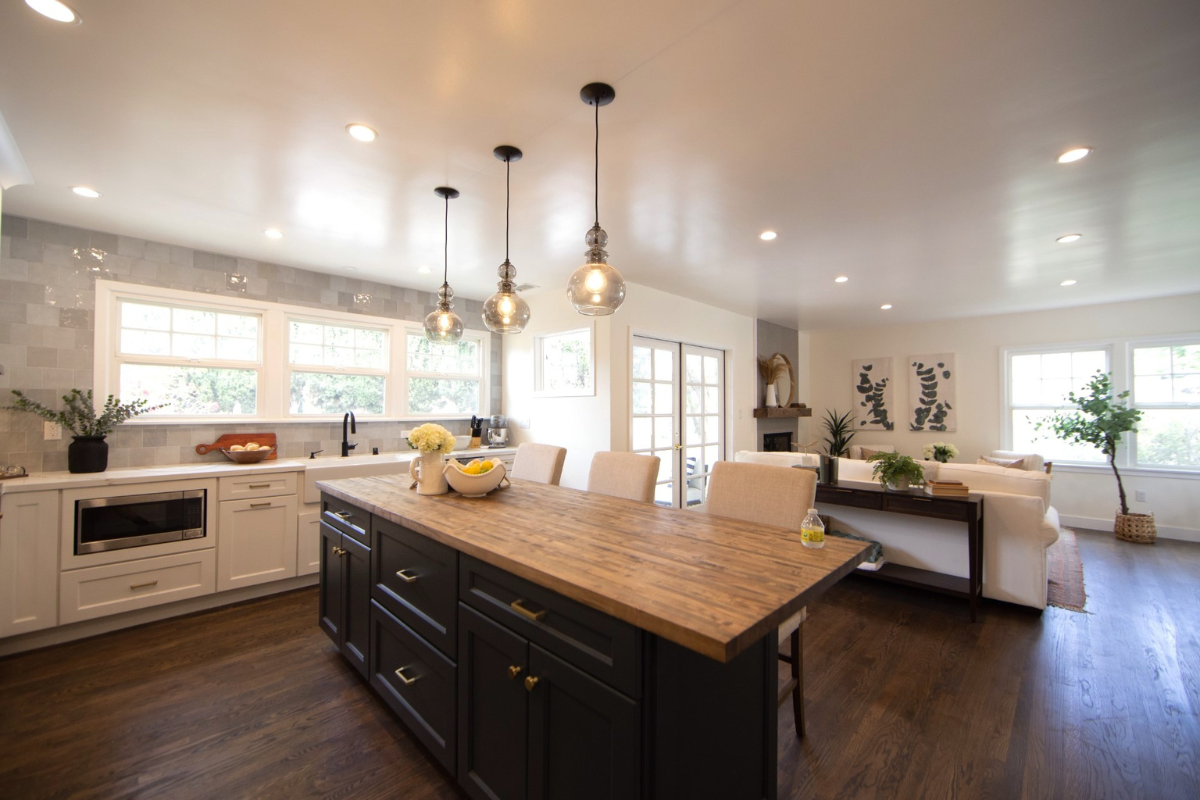 Decorative white shaker kitchen cabinets with white quartz countertops, gold hardware, and an indigo blue island with butcher block countertops