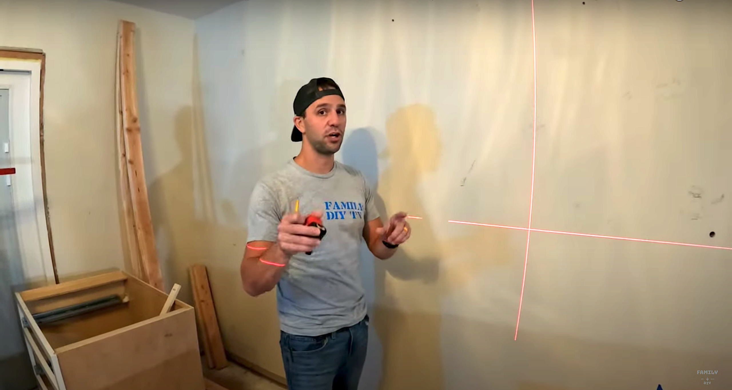 Mike Sante of Family DIY TV using a laser level on his wall before kitchen cabinet installation