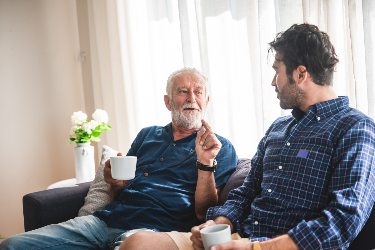 Father talking to his adult son with a cup of coffee