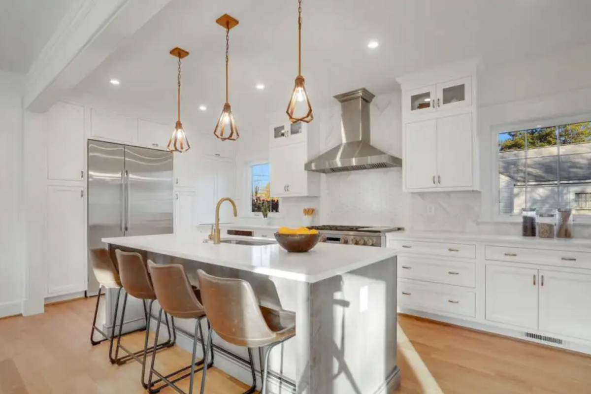 White inset kitchen cabinets with stacked glass cabinets above and a large gray stained kitchen island