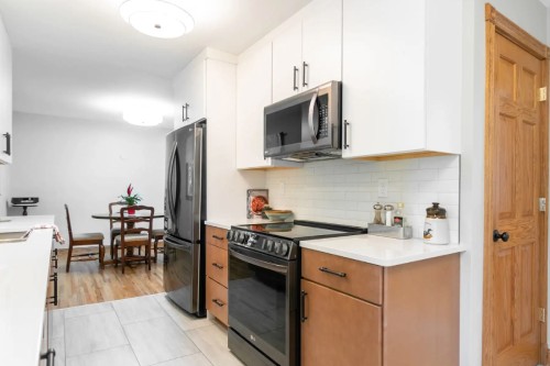 Galley-style slab cabinet door kitchen with white wall cabinets and light wood base cabinets