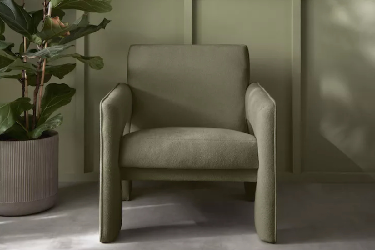 Light avocado green upholstered chair with matching walls behind