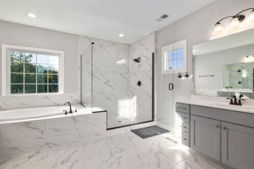 Gray shaker-style vanity with white countertop surrounded by marble