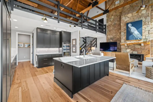 Large black shaker kitchen with stacked cabinets, double-sided island with seating and white marble quartz countertops.