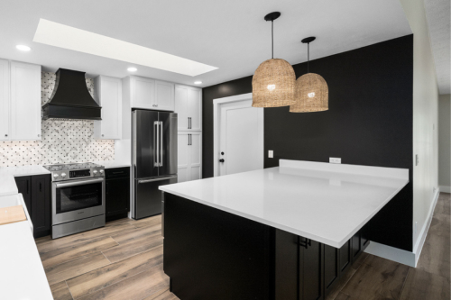 Large L-shaped kitchen design with black shaker base and island cabinets and white shaker wall cabinets with white quartz countertops 