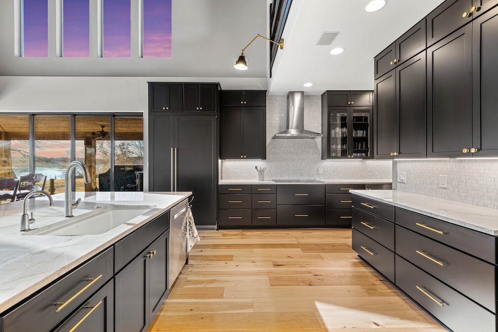 CliqStudios project: Black shaker kitchen cabinets with a white stone countertop and rustic beams above