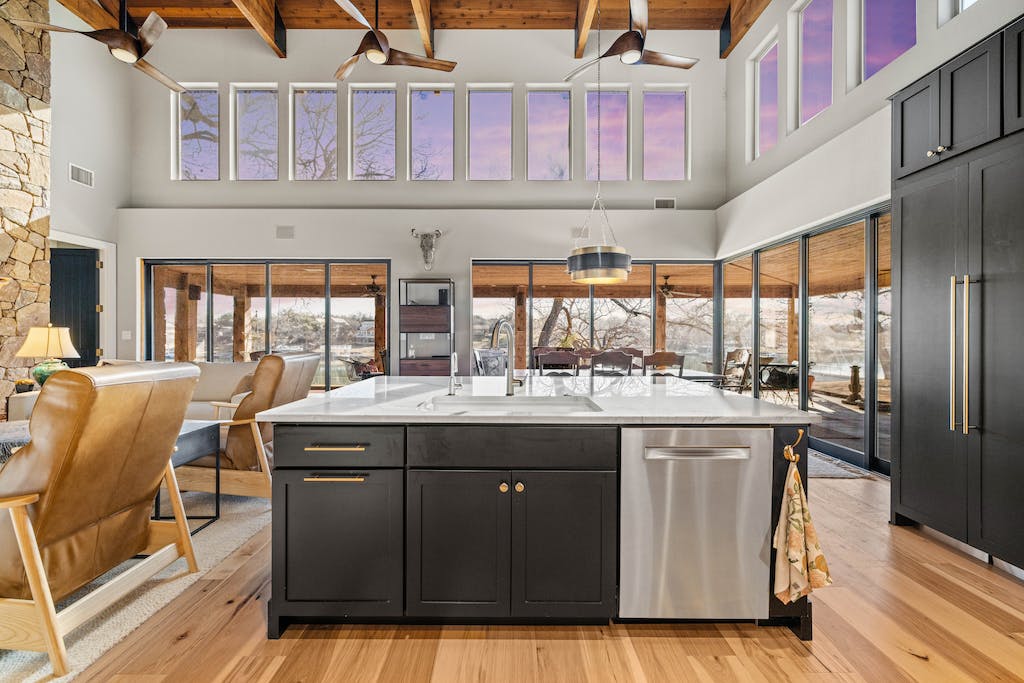 CliqStudios project: Black shaker kitchen cabinets with a white stone countertop and rustic beams above